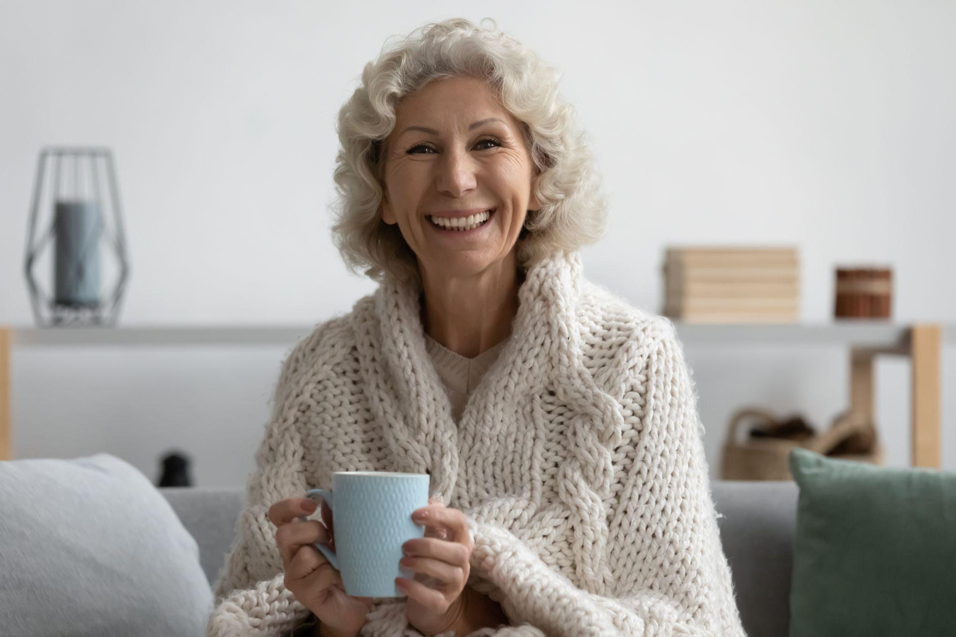 Seniorin mit Tasse in warmem Raum – symbolisiert sichere Waermeversorgung durch mobile Heizzentrale bei Heizungsausfall